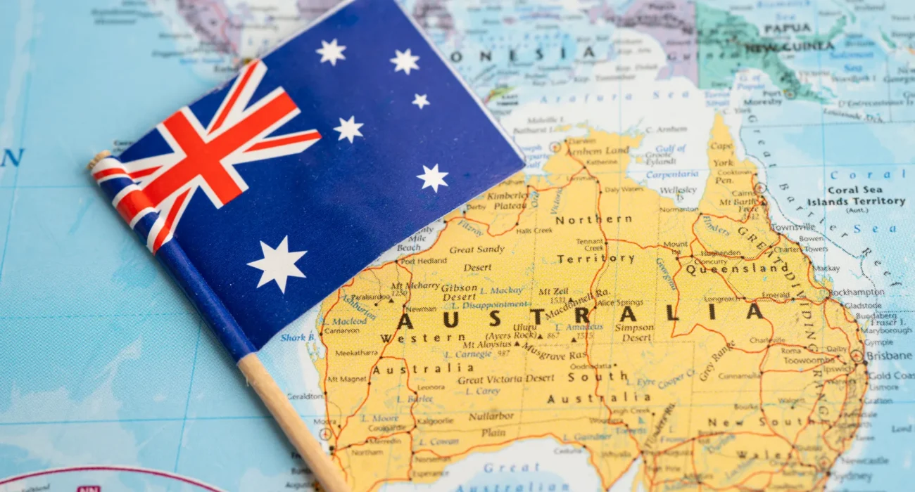 Australian flag resting on a map of Australia, representing migration and settlement.