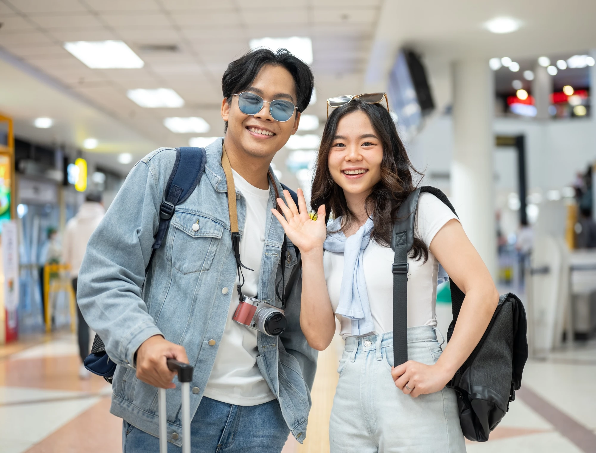 Happy young couple arriving at an Australian airport with luggage, ready to start their PR.